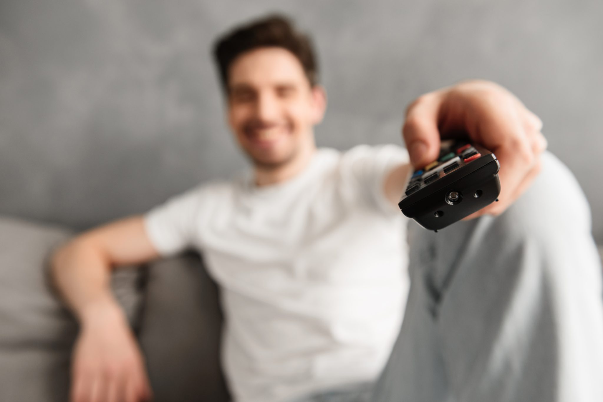 Blurry photo with focus on remote control, young man 30s in casu